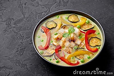 Vegetarian Thai Green Curry with tofu in black bowl at dark slate background. Thailand cuisine dish. Thai Food Stock Photo