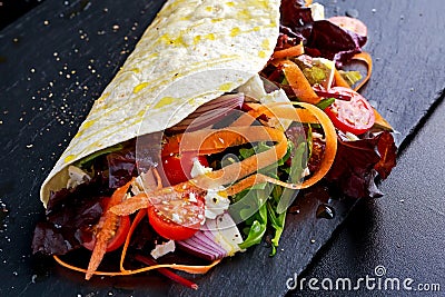 Vegetarian tortillas taco wrap with red onion, sweet cherry tomatoes, carrots, ruby chard, rocket and feta chees Stock Photo