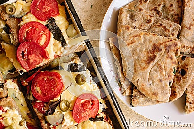 Vegetarian treats pizza with tomatoes, mozzarella and olives and naan with cheese and greens Stock Photo