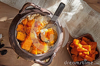 Vegetarian wheat porridge with large chunks of roasted pumpkin in a clay pot in a rustic style organic food Stock Photo