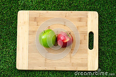 Vegetarians and cooking on the nature of the theme: lying on a cutting board red and green apples on a grass background Stock Photo