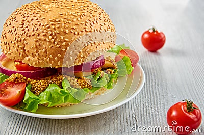 Veggie burger with salad, onion rings decorated with fresh cherry tomatoes on the gray concrete background with free copy space Stock Photo