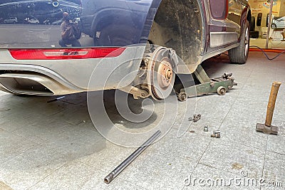 A vehicle being lifted with the help of a hydraulic jack Stock Photo