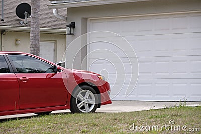 Vehicle parked in front of wide garage double door on paved driveway of typical contemporary american home Stock Photo