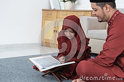 Veil girl learns the Al-Quran with her father Stock Photo