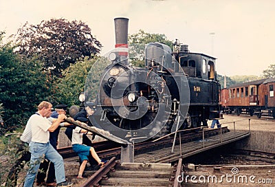 Vejle, Denmark - circa year 1985: Vintage railroad enthusiasts turns the steam locomotive F694 on the small turnable Editorial Stock Photo