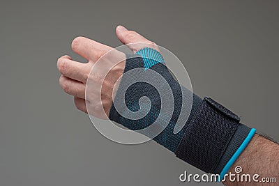 Velcro wrist stabilizer cast worn by Caucasian male hand. A blue split brace meant to aid Carpel Tunnel syndrome. Close up studio Stock Photo