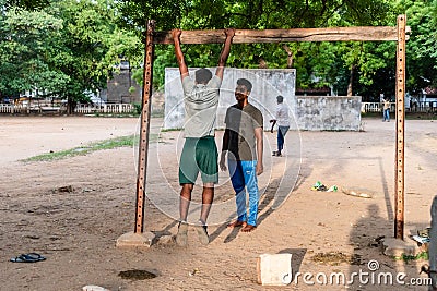 Young Indian boys exercising and doing pull ups on a metal bar in an outdoor Editorial Stock Photo