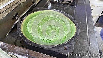 A vendor is cooking sweet pandan martabak. Sweet martabak is cooked using a small skillet Stock Photo