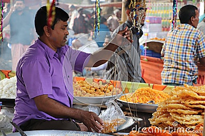 A vendor measuring traditional sweet food Jalebi/Jilapi at a shop of a local market Editorial Stock Photo