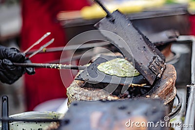 The vendors are making the Thong Muan dessert with iron plate molds on a charcoal stove. Stock Photo