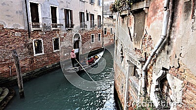 Venetian gondolier floating on a gondola through the waters of the canal between the houses of Venice Italy Editorial Stock Photo