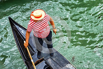 Venetian gondolier punting gondola through green canal waters of Venice Editorial Stock Photo