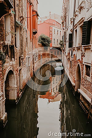Venetian narrow water channels with green water and tall brown old buildings all around. Stock Photo