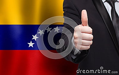 Venezuelan concept. Businessman showing thumb up on the background of flag of Venezuela Stock Photo