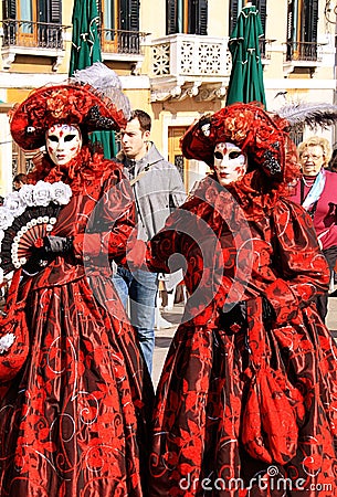 Venice Carnival, two women with red costumes and masks Editorial Stock Photo