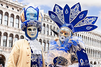 A couple of participants in the Venetian carnival in the original masks on Piazza San Marco Editorial Stock Photo