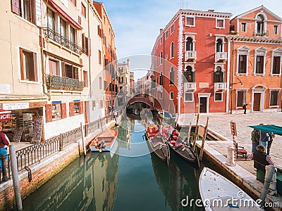 Venice, Italy - 17.10.2023: Gondolas waiting for passengers, Stunning colorful buildings in the background. Warm sunny day. Travel Editorial Stock Photo