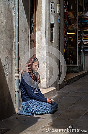 Venice, Italy - May 07, 2018: A homeless female beggar is begging on the street in Venice, Italy. A beggar woman holds a Editorial Stock Photo