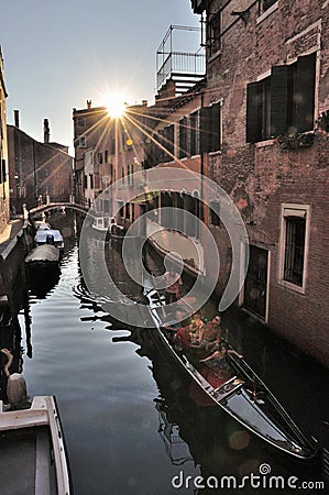 VENICE, ITALY - Sep 23, 2016: typical scene on a canal in Venice, a venetian gondola with gondoliere and tourists at sunset Editorial Stock Photo