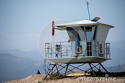 A lifeguard at Ventura Harbor watches from inside a lifeguard tower at a breakwater Editorial Stock Photo