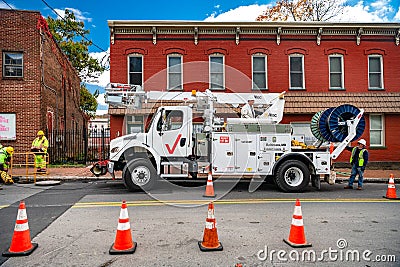 Verizon workmen lowering cable into a manhole (digital composite). Verizon special equipment for Internet debugging Editorial Stock Photo