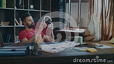 Vermoeide zakenman die voeten op lijst en het luisteren muziek in hoofdtelefoons zetten stock video Vermoeide zakenman die voeten op lijst en het luisteren muziek in hoofdtelefoons zetten stock video