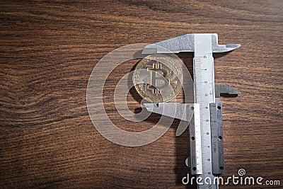 Vernier caliper and Bitcoin on the wooden table Editorial Stock Photo