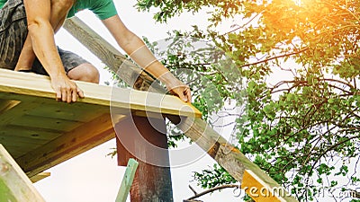 Versatile craftsman working with wood to build a house on a summer day, DIY concept Stock Photo