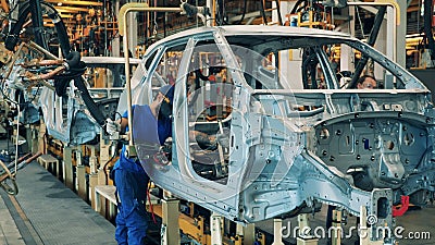Verscheidene werknemers van autofabrieken die een lasmachine op een autoassemblagelijn gebruiken. interieur autofabriek. industrie stock footage Verscheidene werknemers van autofabrieken die een lasmachine op een autoassemblagelijn gebruiken. interieur autofabriek. industrie stock footage