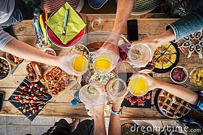 Vertical above view of group of friends differente ages clinking and toasting with glasses - table full of food in the background Stock Photo