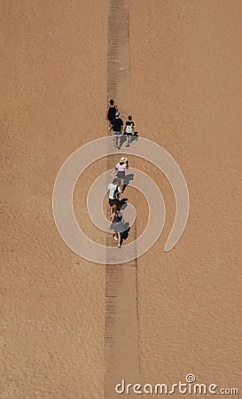 Vertical aerial shot of people walking on a path on sand Stock Photo