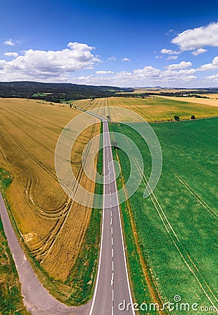 Vertical aerial view of green and yellow harvest fields with tractor and beautiful road. Czech Republic Stock Photo