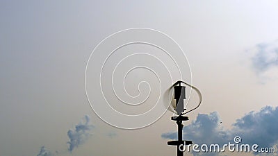 Vertical axis wind turbine utilize renewable wind energy while spinning against blue sky Stock Photo