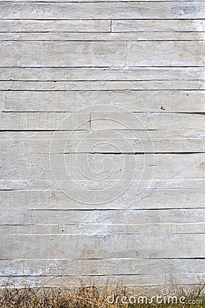 Vertical background of an apparent concrete wall with grass at the base Stock Photo