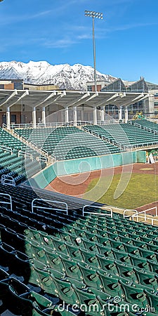 Vertical Baseball field with green tiered seating against mountain and vibrant blue sky Stock Photo