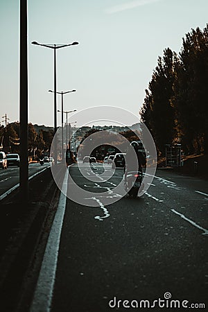 Vertical of a biker on a street of busy traffic in Saint Jean De Luz, France at sunrise Editorial Stock Photo