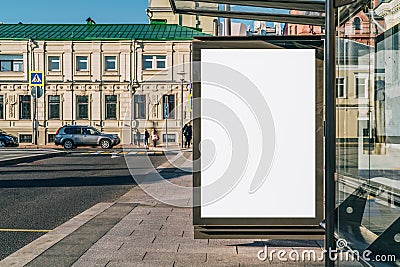 Vertical blank billboard at bus stop on city street. In background buildings, road. Mock up. Poster next to roadway. Stock Photo