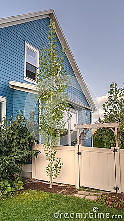 Vertical Blue timber clad house with neat fenced garden Stock Photo