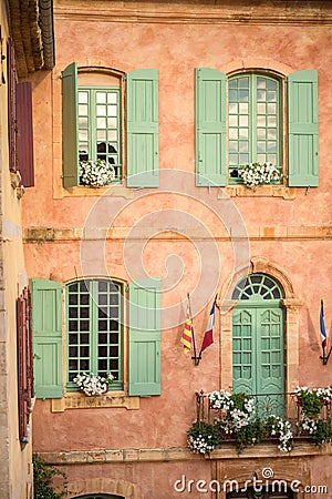 Vertical close-up picture of town hall in Roussillion, Provence, France. Old historical building with orange walls and green Stock Photo