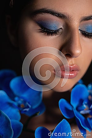 Vertical closeup cool, mysterious, romantic brunette female face with black eyebrows with blue make up and iris flowers Stock Photo