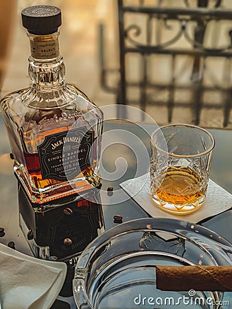 Vertical closeup of a glass and bottle of whiskey on a black glass table Editorial Stock Photo