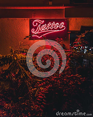 Vertical closeup of a neon tattoo salon sign on a wall illuminated at night Editorial Stock Photo