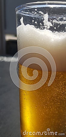 Vertical closeup shot of a glass of bubbling beer with a blurred background Stock Photo