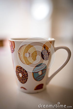 Vertical closeup shot of a mug with a picture of colorful and delicious round donuts Stock Photo