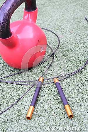 Vertical closeup shot of professional jump rope and a red round heavy weight on artificial grass Stock Photo