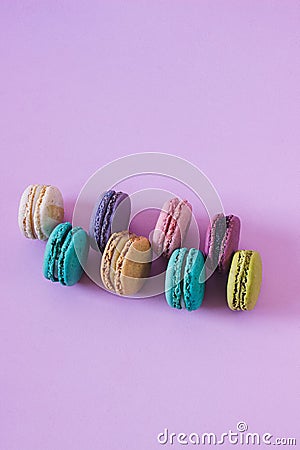 Vertical closeup shot of rows of colorful macarons on a pink background Stock Photo