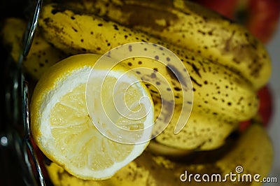 Vertical closeup shot of a squeezed fresh lemon and a bunch of bananas Stock Photo