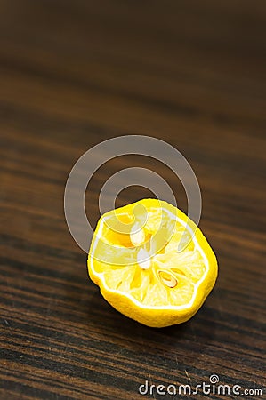 Vertical closeup shot of a squeezed fresh lemon on a wooden surface Stock Photo