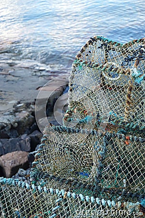 Vertical closeup of weathered prawn traps piled on a dock in western Scotland Stock Photo